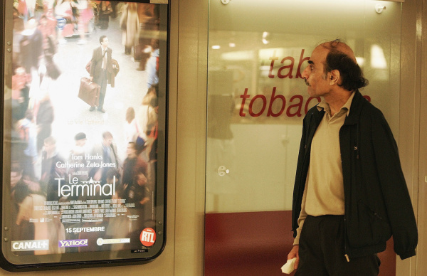 Meram Karimi, frente a cartel de la película La Terminal, inspirada en su vida